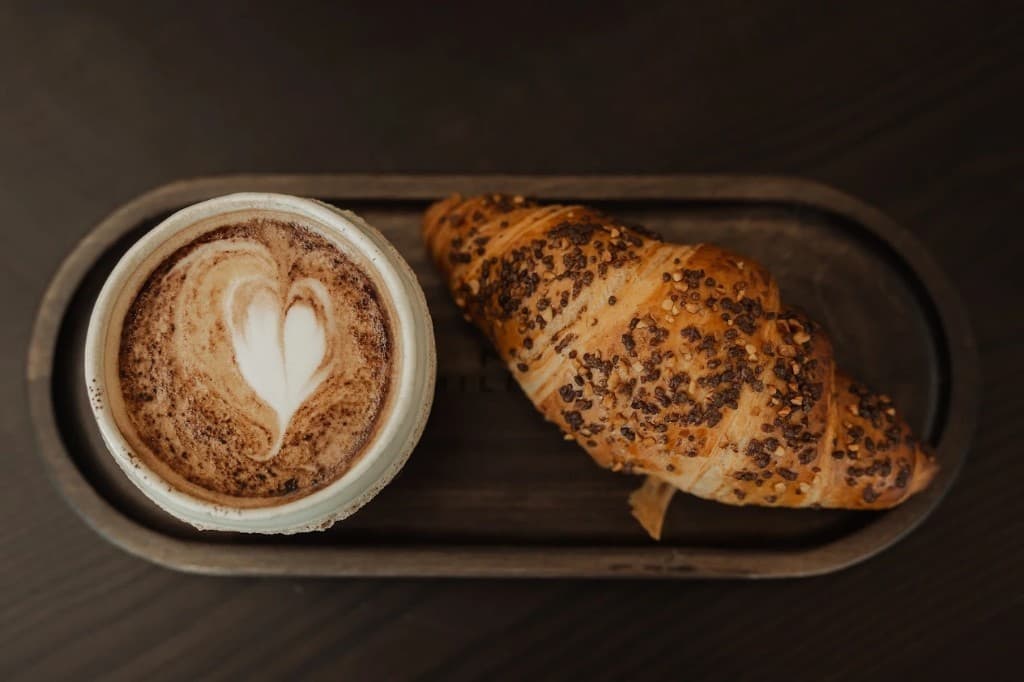 Latte art și croissant cu semințe, pe tava Milese